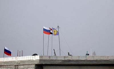 Russian, Syrian and Manbij military council flags flutter near Manbij, Syria on Oct. 15, 2019.