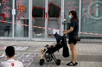A woman with a stroller stands in front of the smashed glass door of the Hong Kong Design Institute during a demonstration in Tiu Keng Leng in Hong Kong, China Oct. 17, 2019.