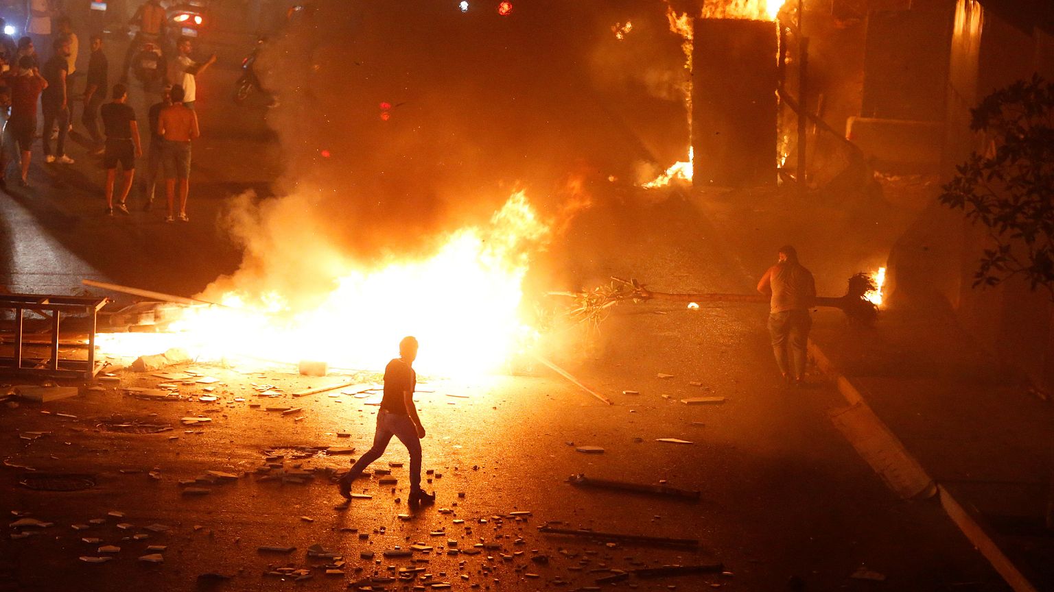 Image: A demonstrator walks close to a fire during a protest over deteriora