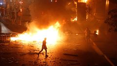 Image: A demonstrator walks close to a fire during a protest over deteriora