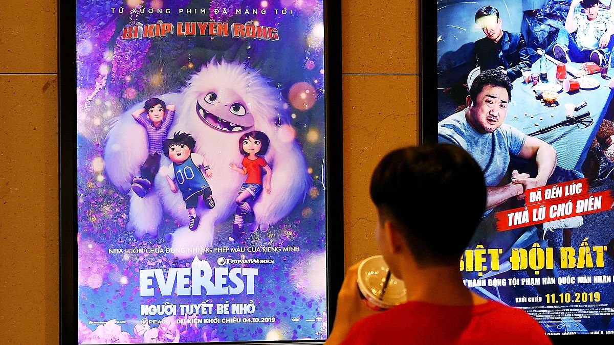 Image: A boy looks at a poster for the animated movie "Everest Nguoi Tuyet 