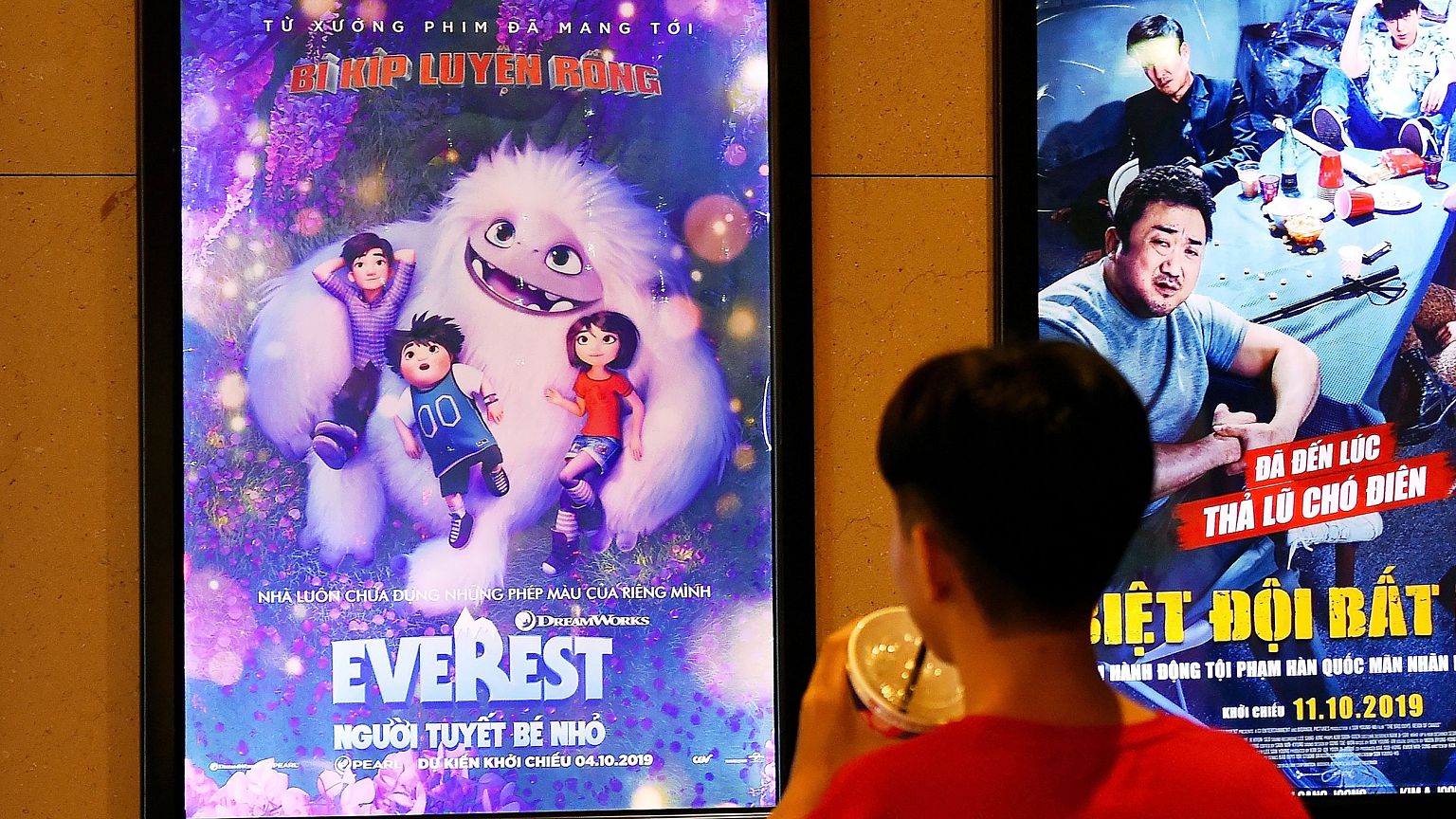 Image: A boy looks at a poster for the animated movie "Everest Nguoi Tuyet 