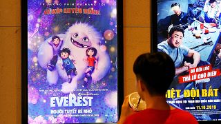 Image: A boy looks at a poster for the animated movie "Everest Nguoi Tuyet