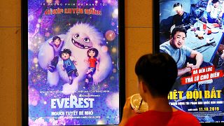 Image: A boy looks at a poster for the animated movie "Everest Nguoi Tuyet 