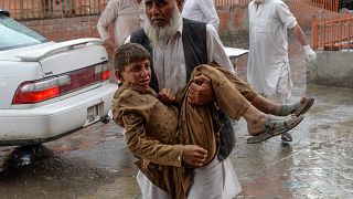 Image: A volunteer carries an injured youth to hospital, following a bomb b