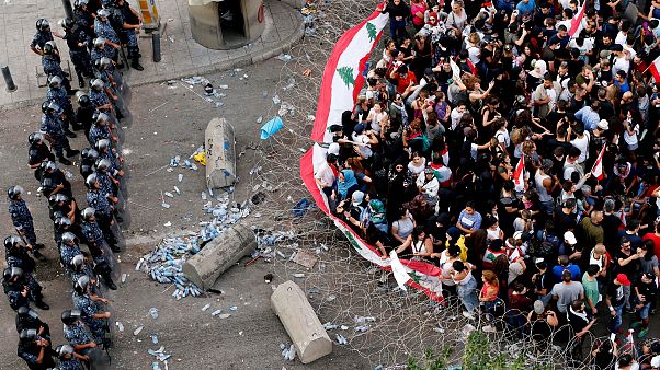 Image: Demonstrators carry flags as police stand behind barbed wire during Image: Demonstrators carry flags as police stand behind barbed wire during