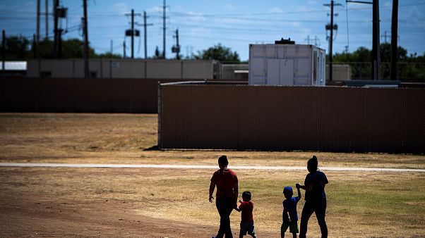 Image: Migrant women and children walk at the South Texas Family Residentia Image: Migrant women and children walk at the South Texas Family Residentia