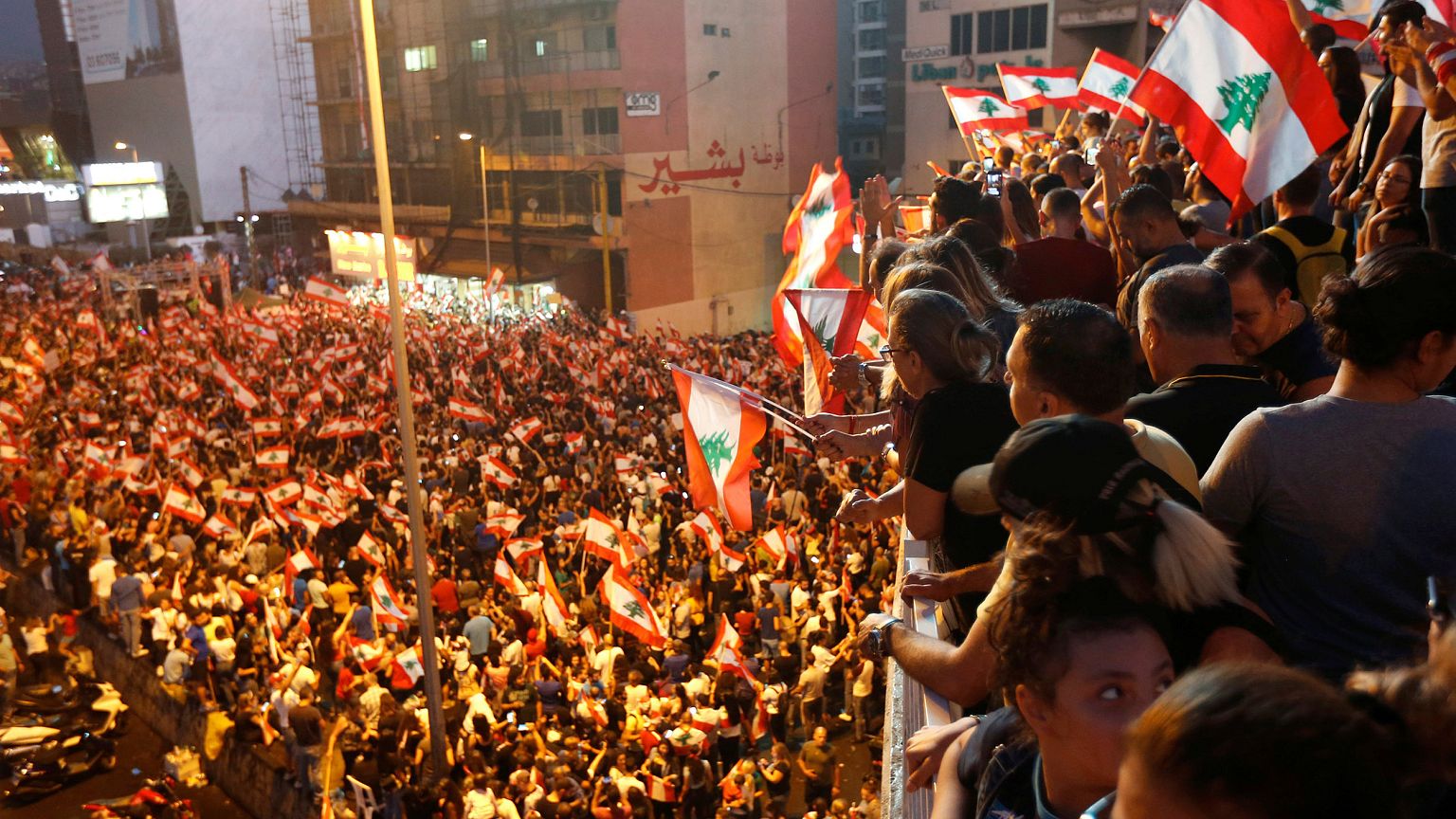 Image: Demonstrators carry national flags as they stand on a bridge during 