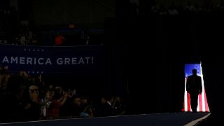 Image: President Donald Trump is silhouetted against a U.S. flag as he hold