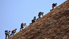 Image: Tourists climb Uluru.