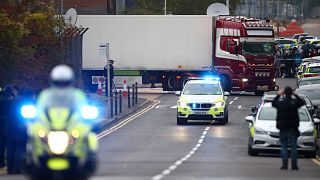 Image: Police officers drive away a lorry in which 39 dead bodies were disc