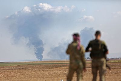Turkey-backed Syrian fighters watch as smoke billows in the distance during clashes between Syrian regime forces, and Turkish forces, near the town of Ras al Ayn, on Wednesday.