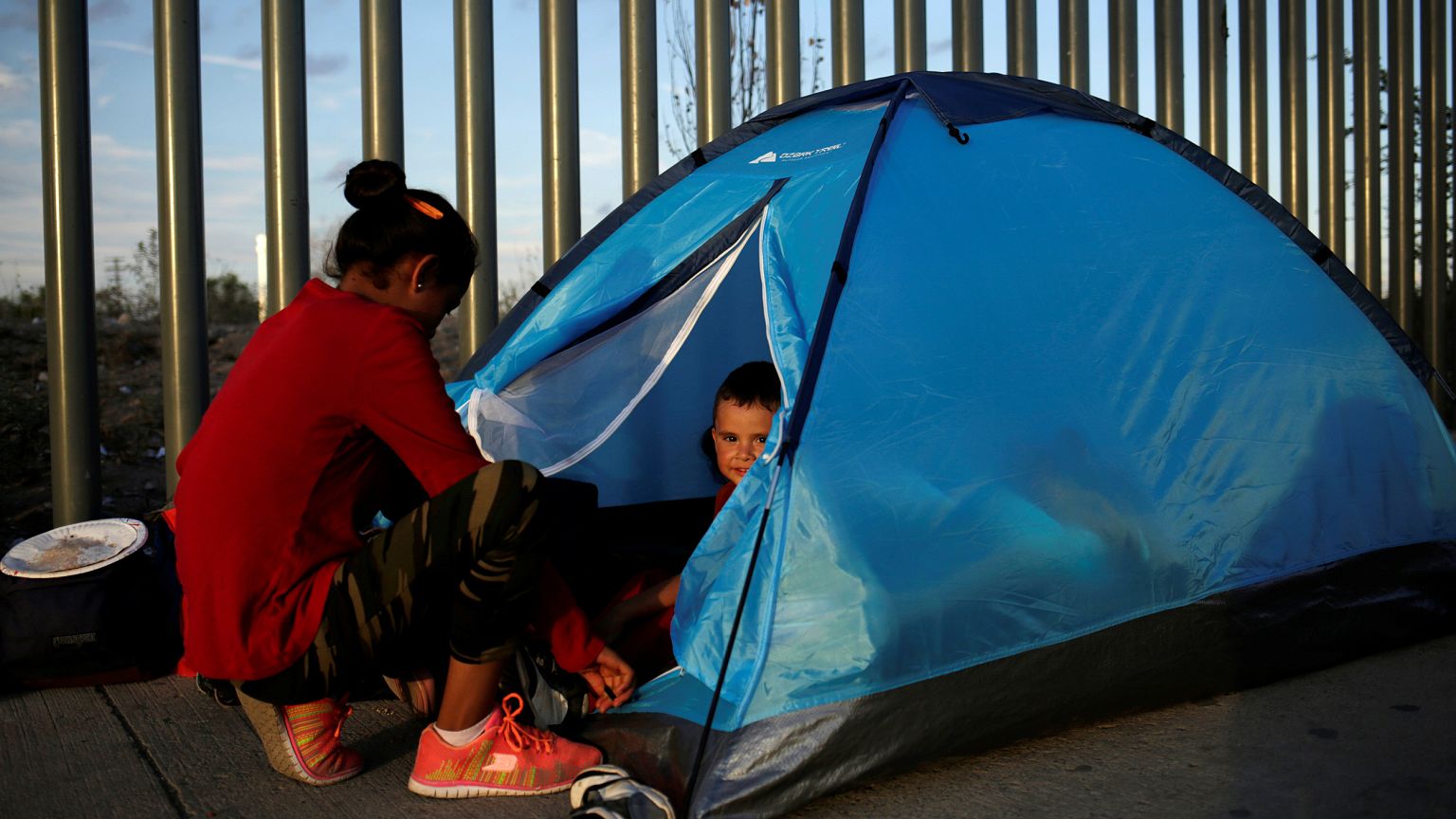 Image: A Mexican citizen fleeing violence camps in a queue with a child to 