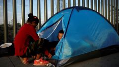 Image: A Mexican citizen fleeing violence camps in a queue with a child to 