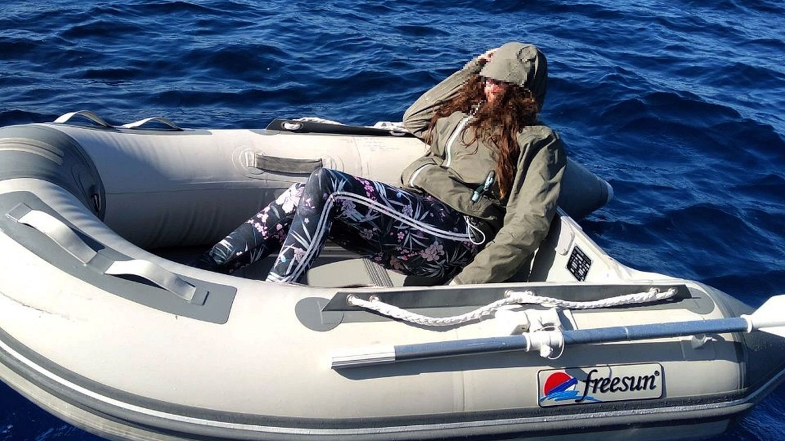 Image: A tourist floats on a small inflatable boat during her rescue by the