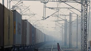 Image: A girl waits to cross the railway line on a smoggy morning in New De