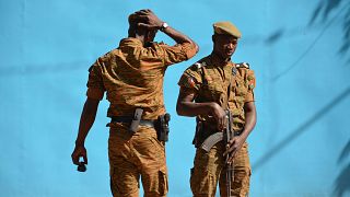 Image: Burkinabe men patrol the army's headquarters from the roof in Ouagad