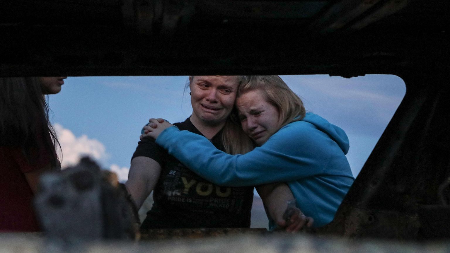 Image: Members of the Lebaron family mourn while they watch the burned car 