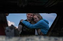 Image: Members of the Lebaron family mourn while they watch the burned car 