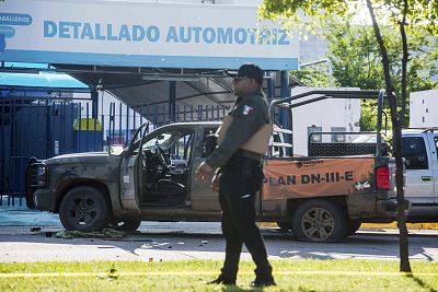 A Mexican police officer inspects the scene around a bullet riddled armed forces truck, a day after gunmen and members of Mexico security forces clashed in a large gun battle in Culiacan, Mexico, on Oct. 18.