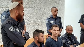 Image: Alexei Burkov, seated second from right, attends a hearing at the Hi