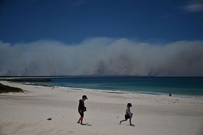 Bush fires burn in the distance as children play on a beach in Forster, 180 miles north of Sydney, on Saturday. 