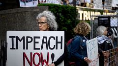 A demonstrator with a sign reading "Impeach now" takes part in Trumps Birth
