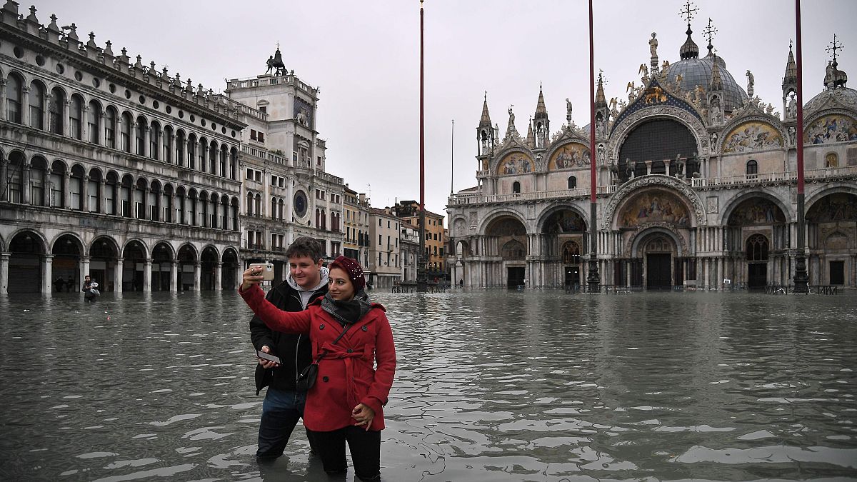 Image: People take selfies in flooded St. Mark's Square by St. Mark's Basil
