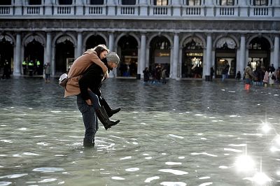 A man carries a woman on his back through the flooded St. Mark\'s Square during a period of seasonal high water in Venice, Italy, Thursday. 