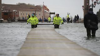 Image: Municipality workers carry wooden boards to make a trestle bridge in