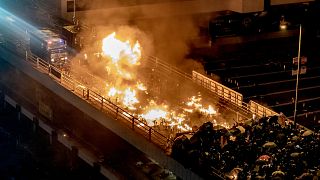 Image: A police vehicle burns as protesters and police clash on a bridge at