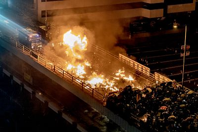 A police vehicle burns as protesters and police clash on a bridge at The Hong Kong Polytechnic University on Nov. 17, 2019.