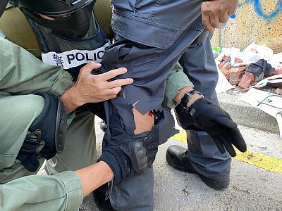 In this photo released by the Hong Kong Police Department, police prepare to remove an arrow from the leg of a fellow officer during a confrontation with protestors at the Hong Kong Polytechnic University Sunday.