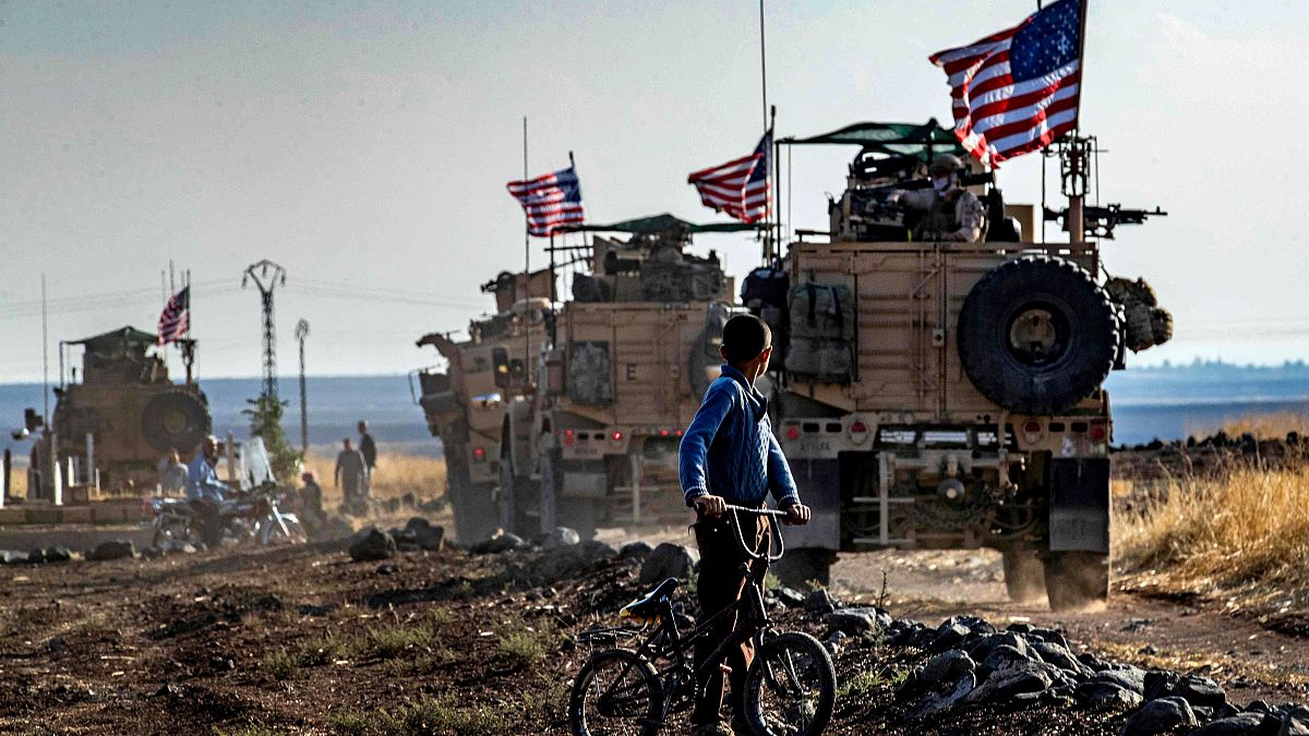 Image: A Syrian boy looks at a U.S. convoy patrolling near the Turkish bord