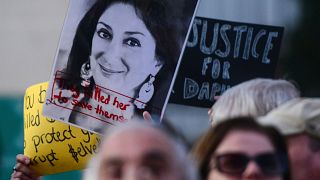 Image: Protesters holding a photo of killed reporter Daphne Caruana Galizia