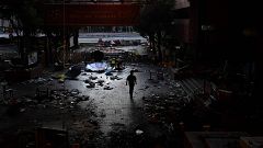 Image: A man walks past debris littering the entrance at the Hong Kong Poly