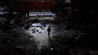 Image: A man walks past debris littering the entrance at the Hong Kong Poly