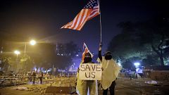 Image: Protesters hold British and American flags and a sign reading "Save 