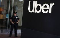 Image: A San Francisco police officer monitors a protest outside of Uber he