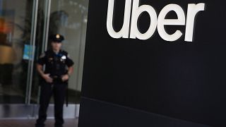 Image: A San Francisco police officer monitors a protest outside of Uber he
