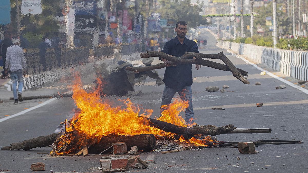 Image: A protester sets fire to block traffic in Gauhati, India
