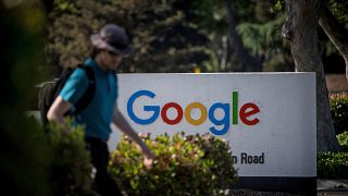 A pedestrian walks past signage at Google headquarters in Mountain View, Ca