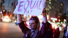 Image: A woman holds a sign that reads, "Equal Pay" during "A Day Without A