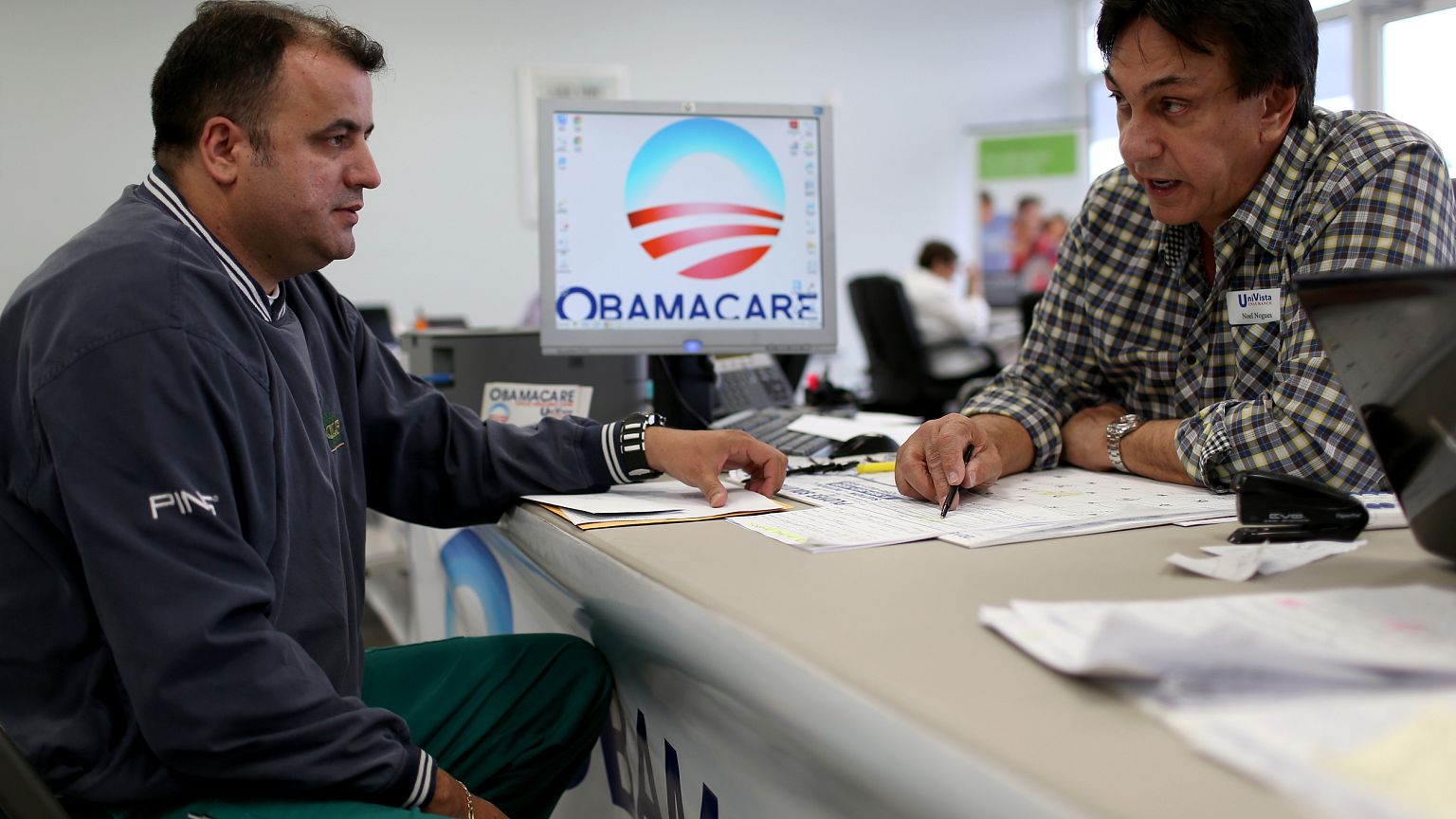 Image: Ariel Fernandez, left, sits with Noel Nogues, an insurance adviser, 