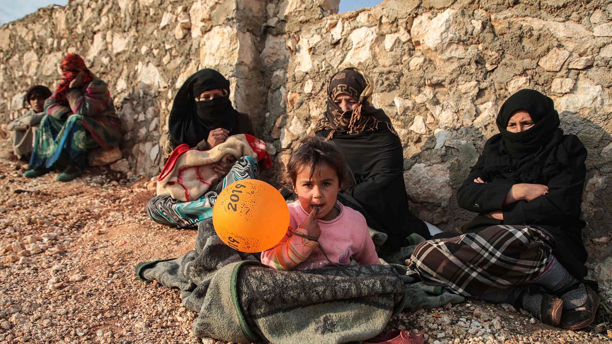 Image: Displaced civilians from the south of Idlib province sit out in the 