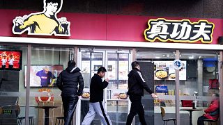 Image: People walk past the restaurant Real Kung Fu, or Zhen Gongfu in Mand