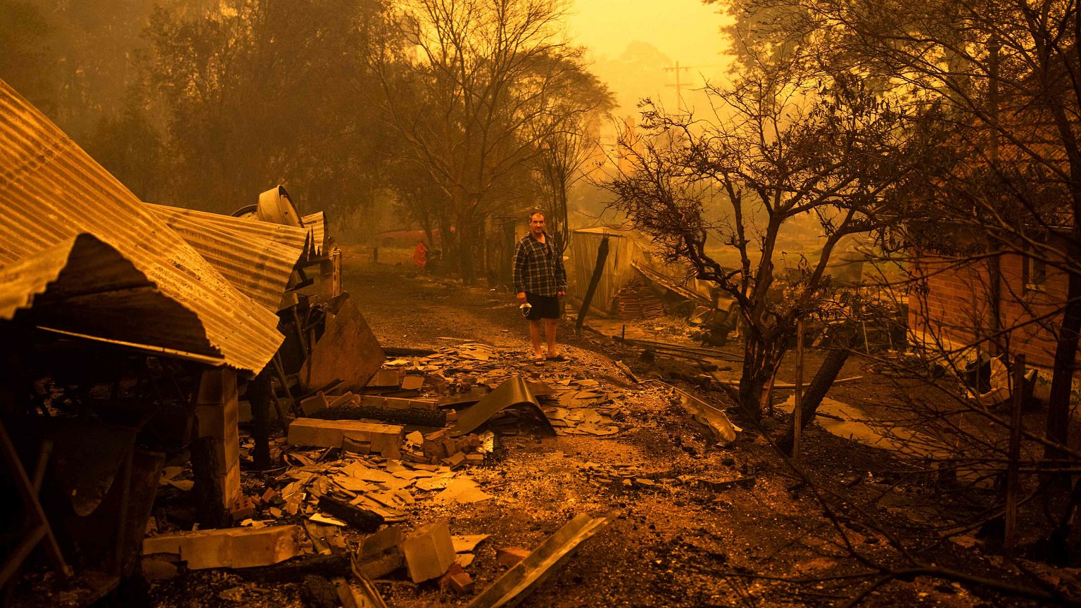 Image: Gary Hinton stands in the rubble after fires devastated the town of 