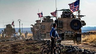 Image: A Syrian boy looks at a U.S. convoy patrolling near the Turkish bord