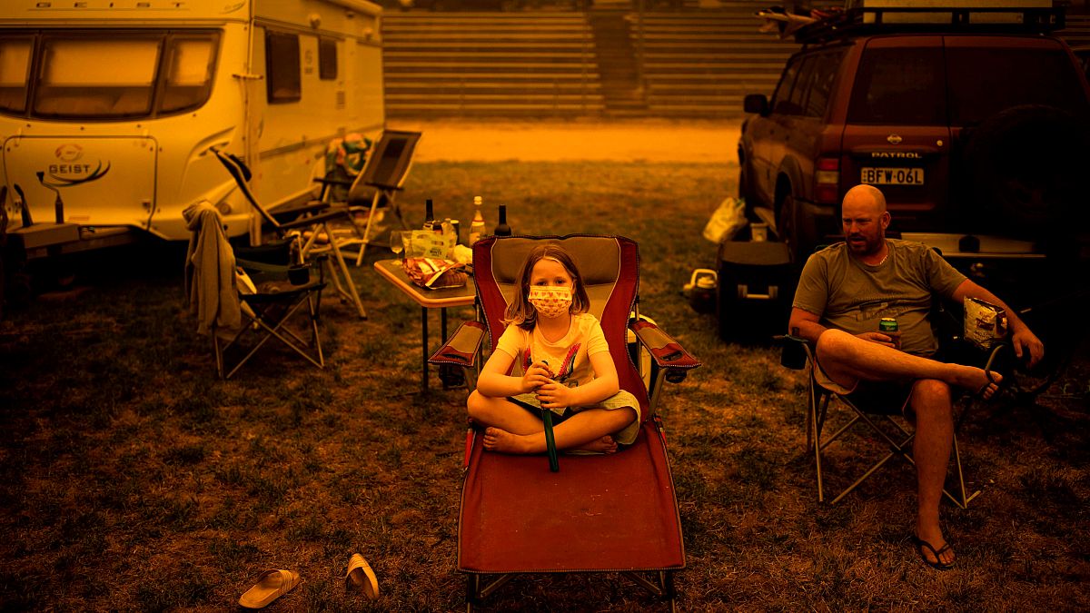 Image: Amy and Ben Spencer sit at a Bega campground after being evacuated f