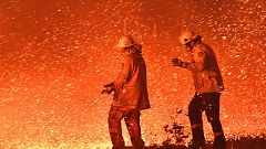 Firefighters struggle against the strong wind in an effort to secure nearby